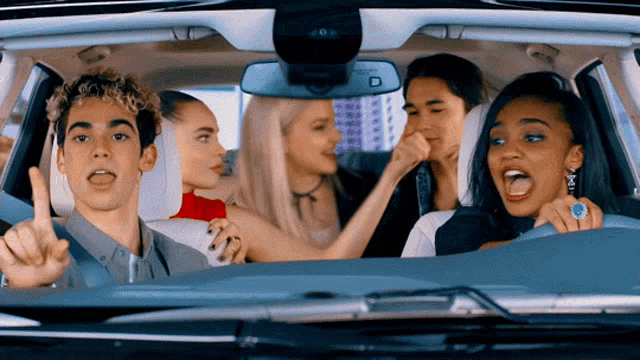 a group of young people are sitting in a car and one of them is pointing up