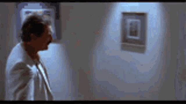 a man is looking at a picture on a wall in a dark room .