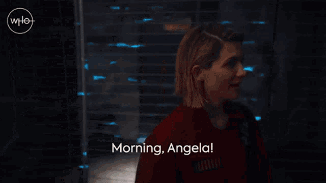 a woman says " morning angela " in front of a brick wall