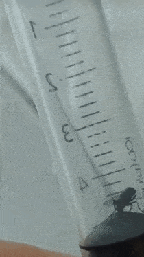 a small bug is sitting on top of a syringe with the letter s visible