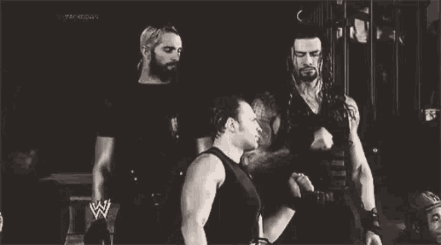 a black and white photo of wrestlers with a w logo on their chest