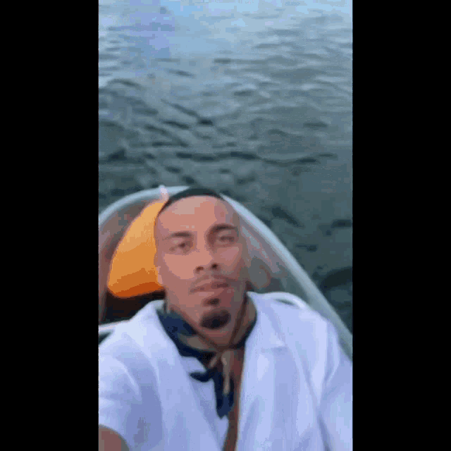 a man in a white shirt and tie is taking a selfie in a boat .