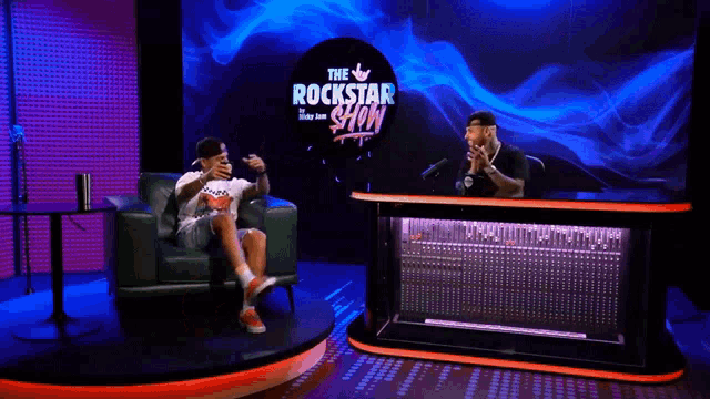 a man sitting on a couch in front of a sign that says the rockstar show