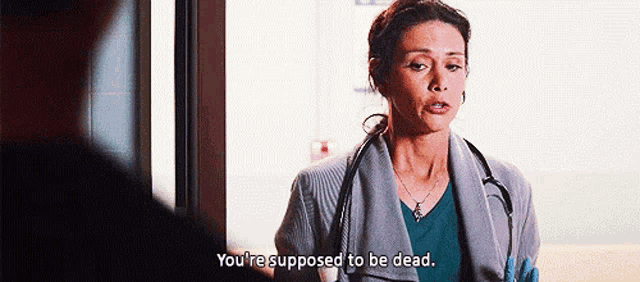 a woman with a stethoscope around her neck is talking to a man in a hospital room .