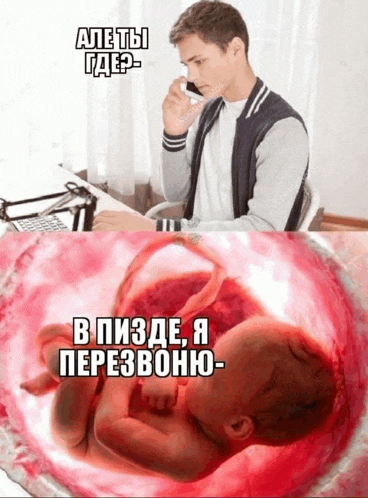 a man sitting at a desk talking on a cell phone next to a picture of a baby in the womb