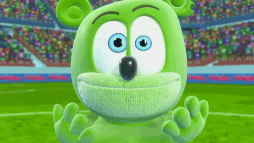 a green gummy bear with blue eyes is sitting in front of a stadium .