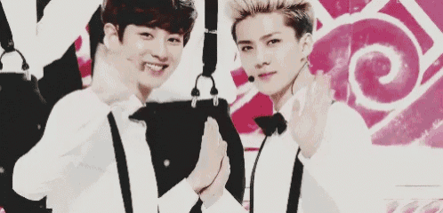 two young men in tuxedos and bow ties are standing next to each other on a stage .