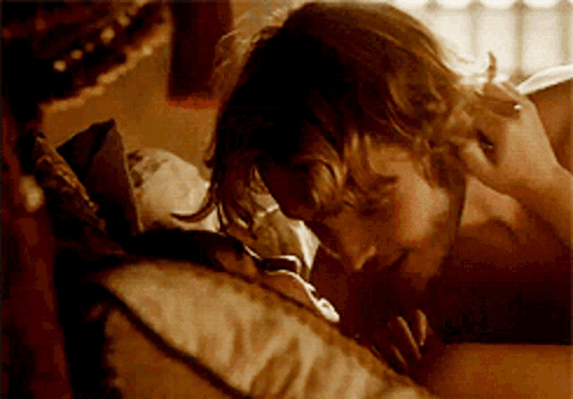 a man and woman are laying on a bed and the woman is touching the man 's face