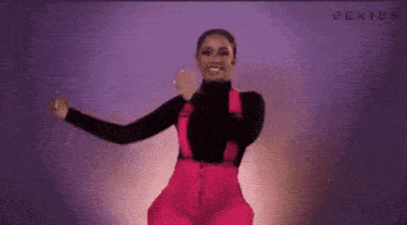 a woman in pink overalls and a black turtleneck is dancing .