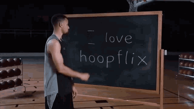 a man stands in front of a chalkboard that says love hoopflix on it