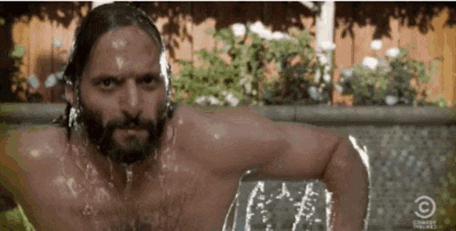 a man with a beard is taking a bath in a pool with comedy central written on the bottom