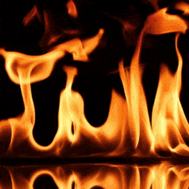 a close up of flames on a black background with a reflection of the flames