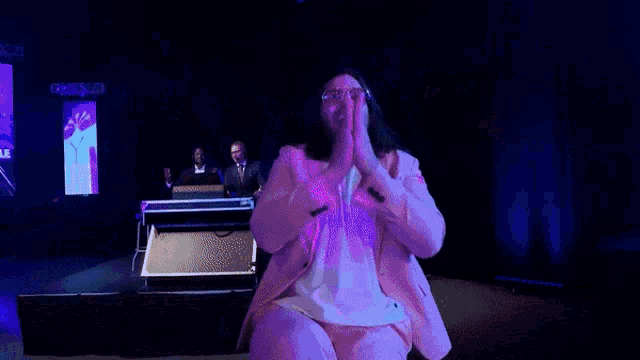 a woman in a pink suit is clapping her hands