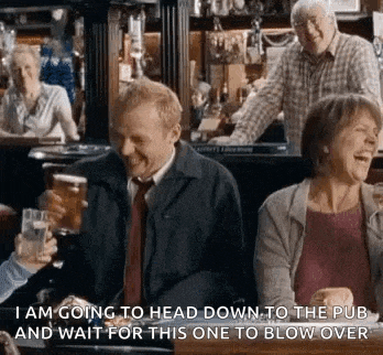 a group of people are sitting at a table in a pub drinking beer .