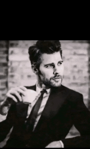 a man in a suit and tie is holding a cup of coffee in his hand