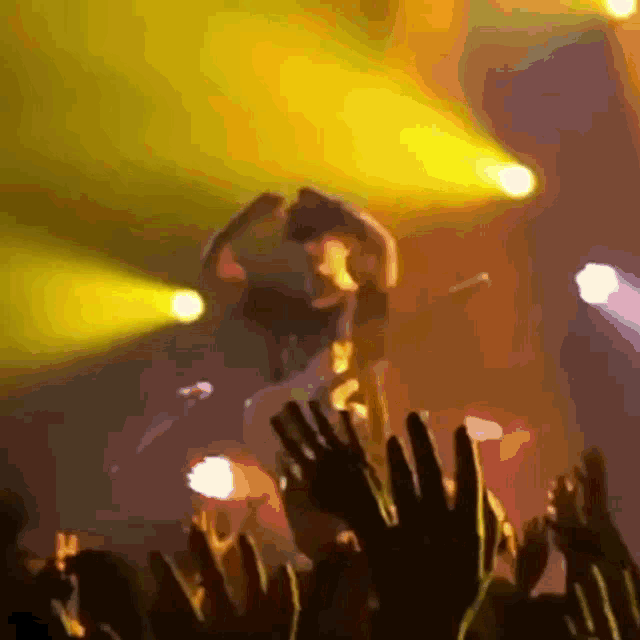a crowd of people raising their hands in the air at a music concert