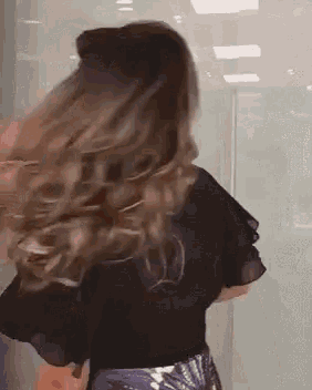 the woman is wearing a black top and a purple skirt and her hair is blowing in the wind .