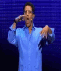 a man in a blue shirt is making a funny face with his hands .