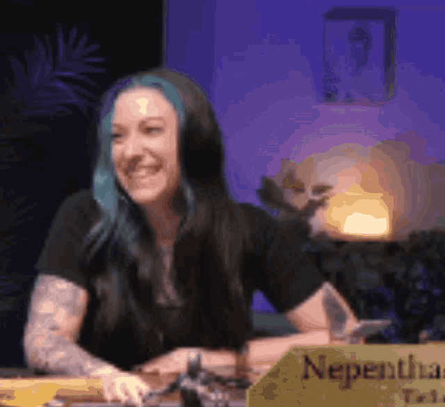 a woman with blue hair is sitting at a table with a yellow sign that says nepentha on it