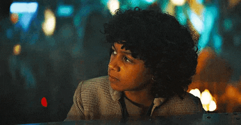 a young boy with curly hair is sitting in front of a fire .