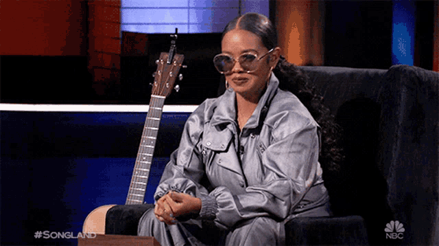 a woman is sitting in a chair with a guitar behind her .