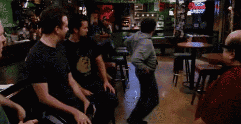 a group of people are sitting in a bar and a man is dancing in the background .