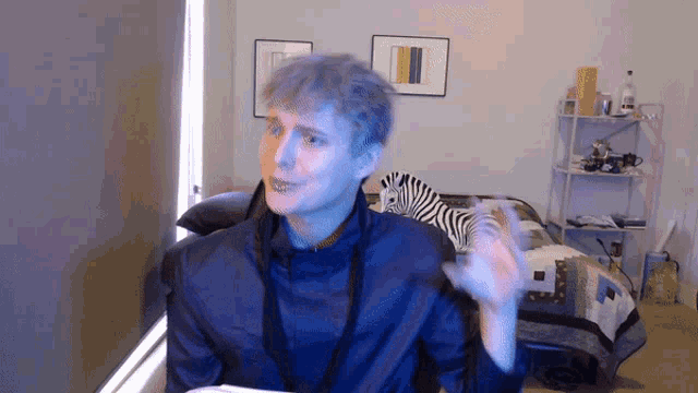 a man in a blue jacket is sitting in front of a zebra