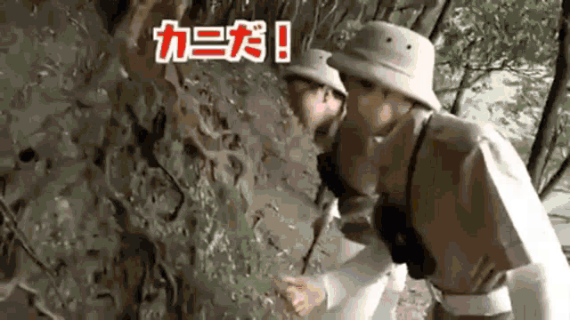 a group of people are standing next to each other in a forest looking at a snake .