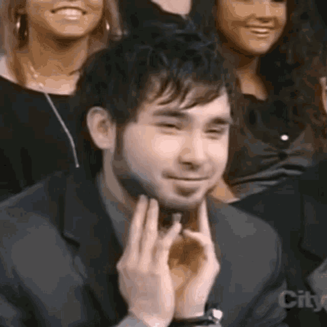 a man in a suit is sitting in front of a group of people and smiling .