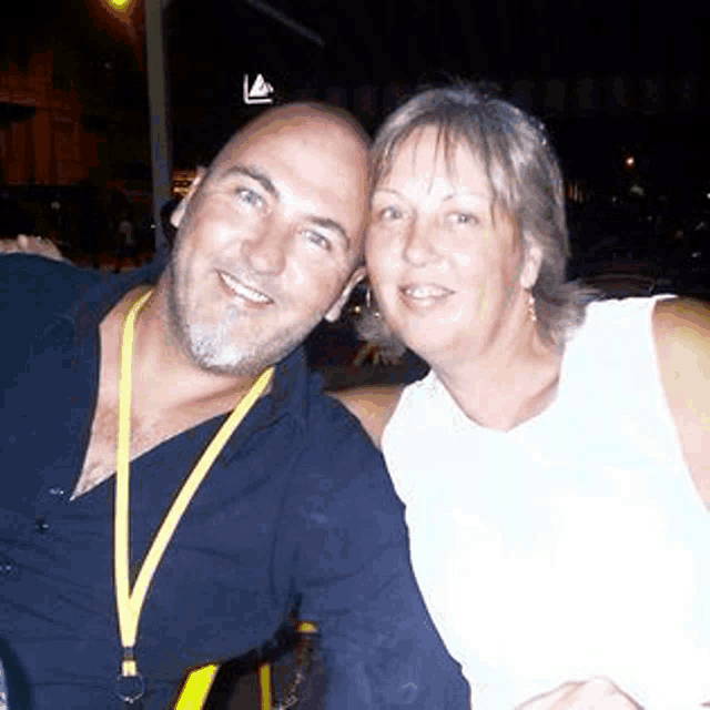 a man and a woman are posing for a picture together and smiling for the camera .