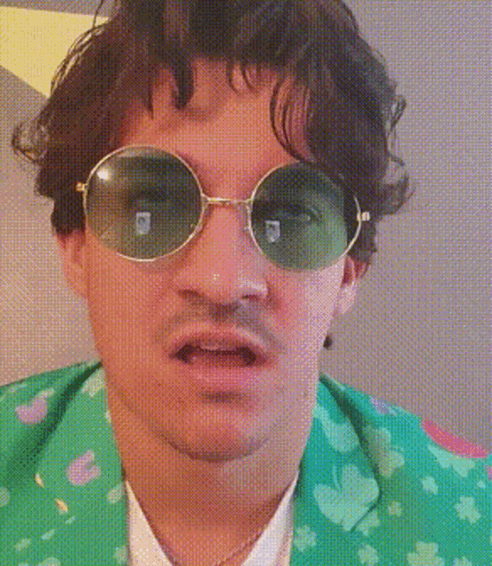 a man wearing sunglasses and a green jacket with clovers on it