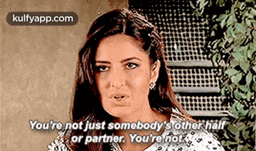 a woman is standing in front of a fence and talking to someone .