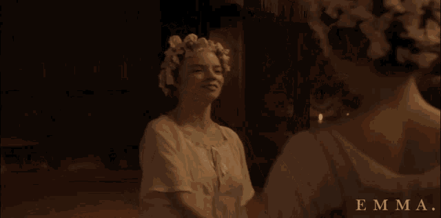 a woman with flowers in her hair is standing in front of a mirror with the name emma written below her