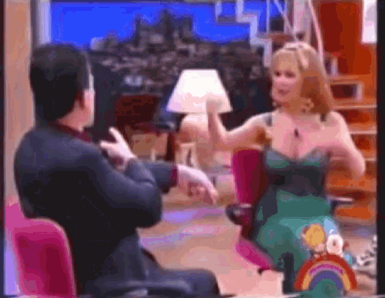 a woman in a green dress is talking to a man in a black suit
