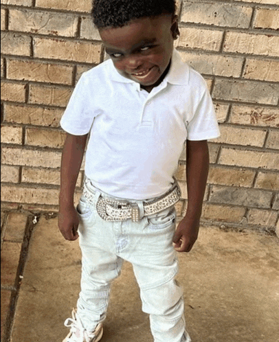 a young boy wearing a white polo shirt and white jeans
