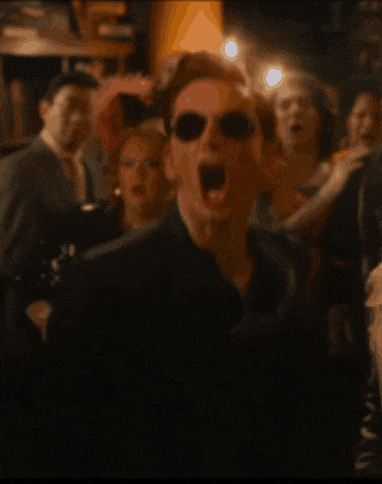 a man wearing sunglasses is standing in front of a crowd
