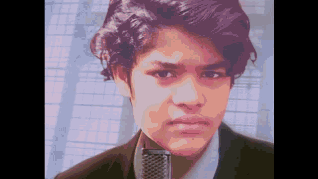 a young boy in a suit and tie holds a microphone in front of his face