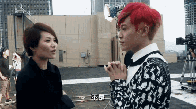 a man with red hair talks to a woman with chinese writing