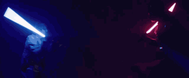 two lightsabers are being used in a dark room