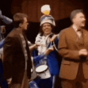 a group of people are standing next to each other on a stage . one of the people is holding a drum .