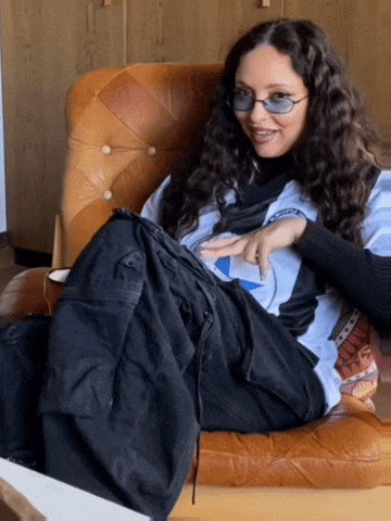 a woman is sitting in a chair wearing sunglasses