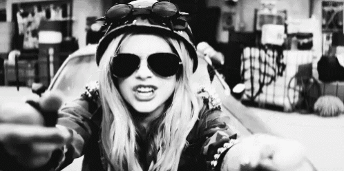 a woman wearing sunglasses and a helmet is pointing at the camera .