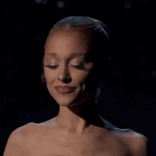 a woman without a shirt is smiling and looking down