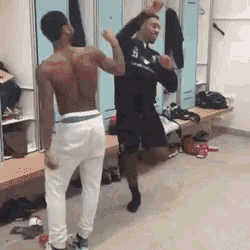 a shirtless man is dancing in a locker room with other men