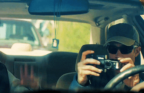 a man in a car taking a picture with a kodak camera
