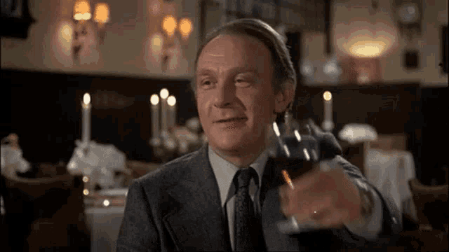 a man in a suit and tie is holding a glass of wine in his hand .