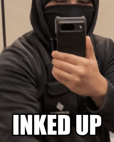 a man is taking a picture of himself in a mirror with the words " inked up " on the bottom