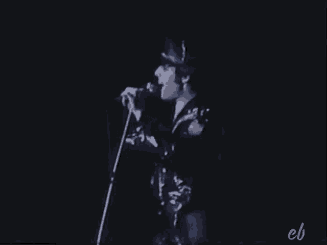 a man is singing into a microphone on a stage in a black and white photo .