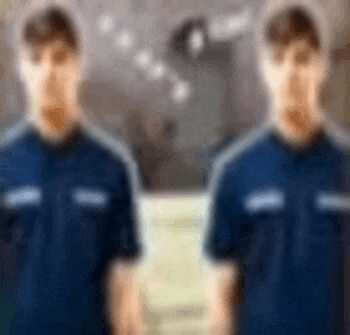 a blurry picture of two men standing next to each other in blue shirts .