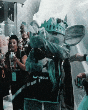 a mascot wearing a green crown and a webull vest